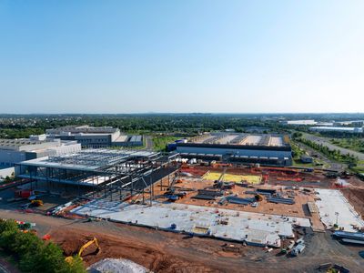 A large construction site with steel framework and concrete slabs under clear blue sky.