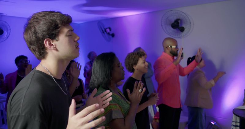 Diverse congregation worships in church with hands lifted and eyes closed, people united in faith during vibrant praise session