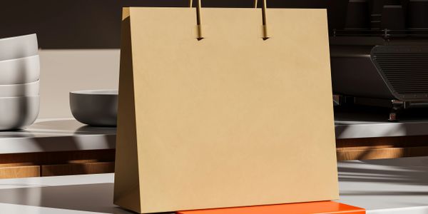 A plain brown paper shopping bag on a kitchen counter with bowls and a coffee machine.