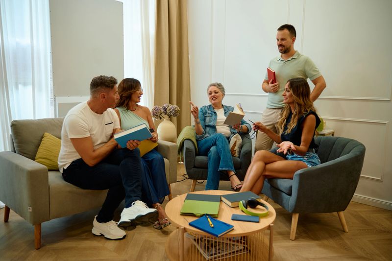 Happy friends meeting for a book club discussion in a comfortable living room. Sharing ideas and enjoying social time together