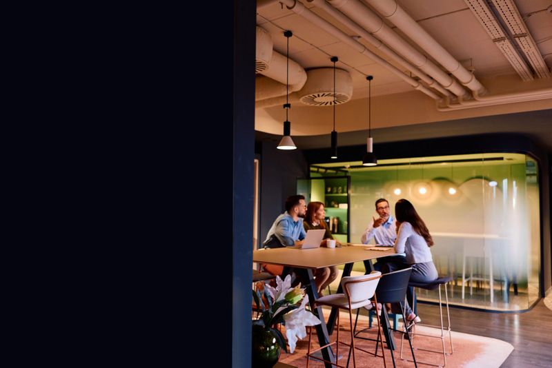 Group of diverse business colleagues actively brainstorming and discussing new strategies during a teamwork meeting in a contemporary and stylish office environment