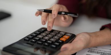 Person using a calculator while holding a pen.