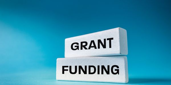 Two white blocks with the words 'GRANT' and 'FUNDING' on a blue background.