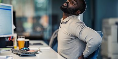 Man holding his lower back in pain after long hours sitting at a desk