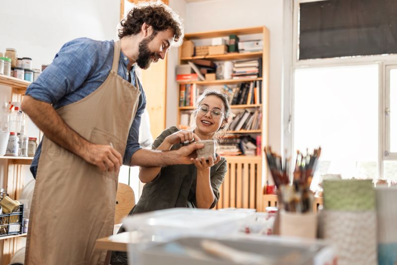 Two Pottery Artists Shaping Clay in Group Workshop