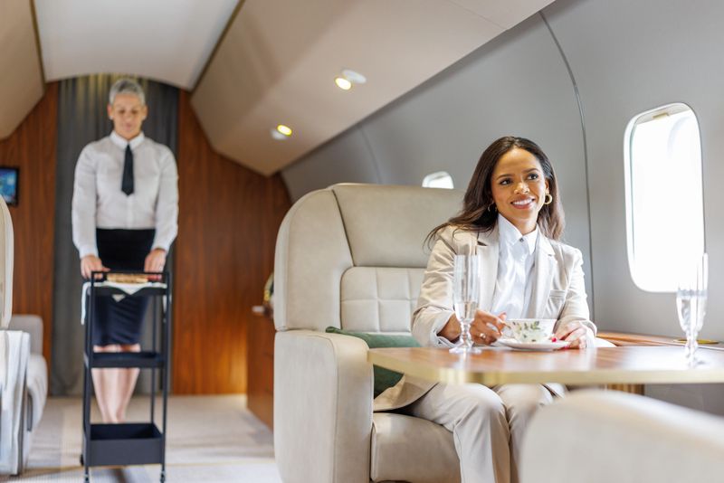 Businesswoman travels in luxury while a flight attendant provides premium service on a business jet