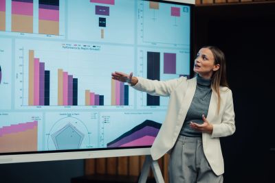Woman presenting data charts on a large screen.