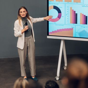 Businesswoman giving presentation with data charts on screen.