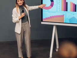 Businesswoman presenting data charts on a screen during a meeting.