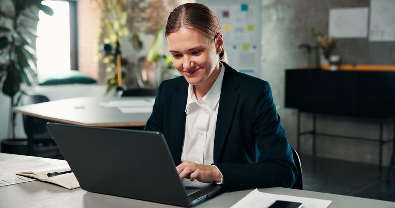 Business, woman and typing on laptop in office for research, email client and policy update. Female person, smile and pc for insurance application, claims information or data entry of risk assessment