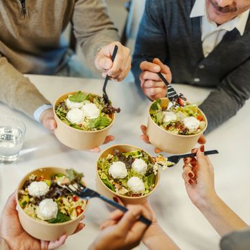 Four people enjoying fresh salads with cheese in bowls.