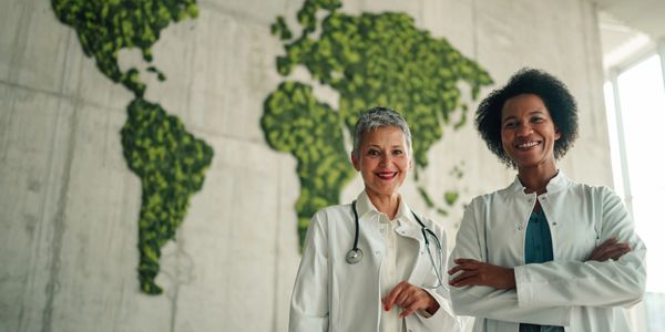 Two confident doctors standing in front of a world map made of greenery.