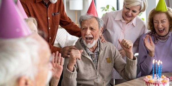 Elderly man joyfully celebrating his birthday with friends.