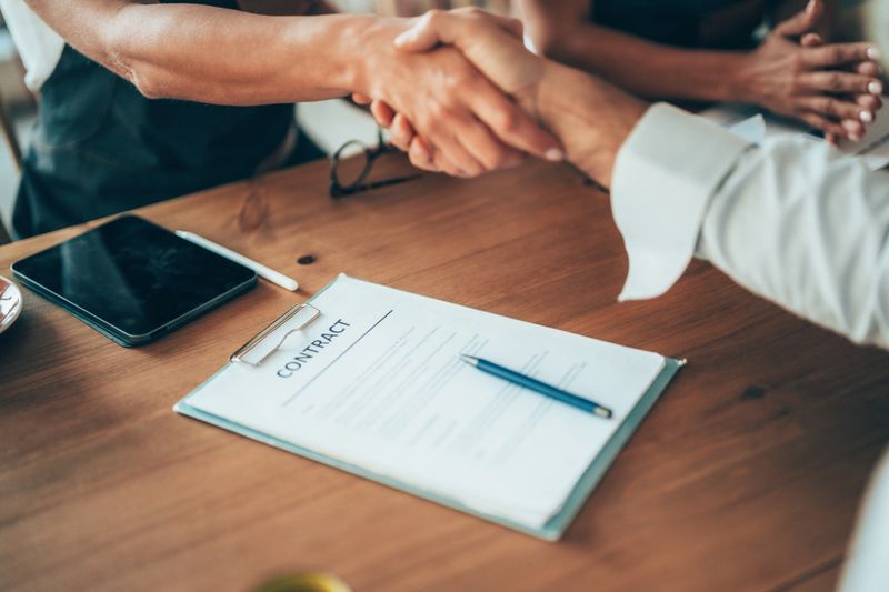 Close-up of business partners shaking hands over a signed contract