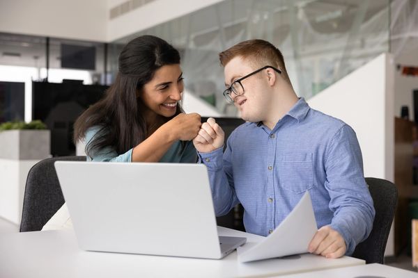 Two people in front of a laptop exchanging a fist pump in celebration of an accomplishment