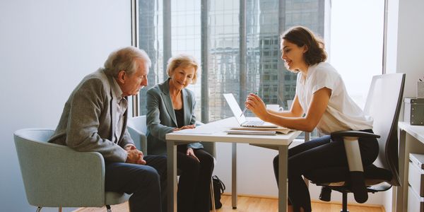Young professional consulting with elderly clients in office.