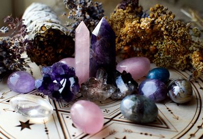 Assorted crystals and dried herbs arranged on a mystical patterned surface.