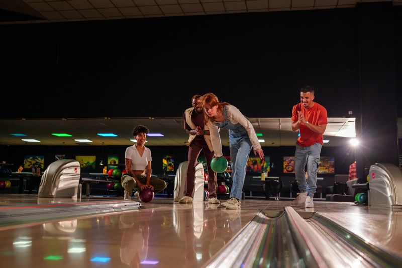 Group of friends enjoying a lively bowling session at the bowling alley, sharing laughter and excitement while competing and bonding together