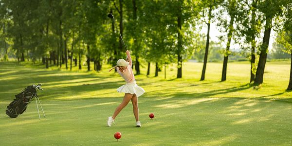Woman swinging golf club on a sunny golf course surrounded by trees. Of course she has her Toe Down!