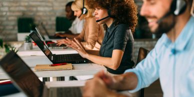 Equipe de suporte trabalhando com headsets em laptops.