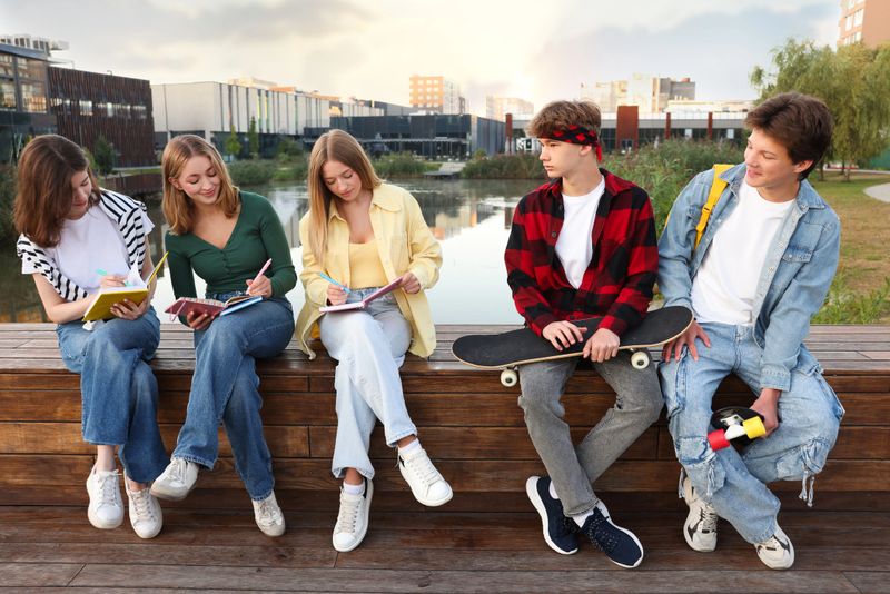Group of teenagers doing homework together outdoors