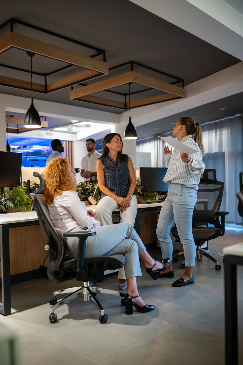 Group of diverse business professionals engaged in discussion inside modern office, highlighting teamwork, leadership, and communication