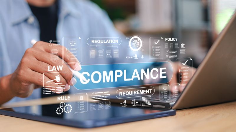 Businessman using digital tablet with virtual interface showing compliance, law, regulation, policy, and requirement. Corporate governance and data protection concept.