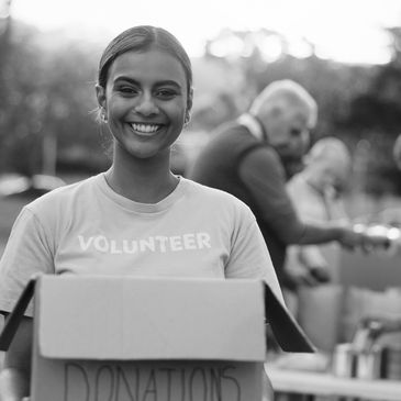 Smiling volunteer holding donation box outdoors.