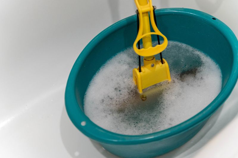 Turquoise basin filled with bubbles and a yellow cleaning tool, showcasing the essence of household cleaning, maintenance, and vibrant colors in a domestic setting