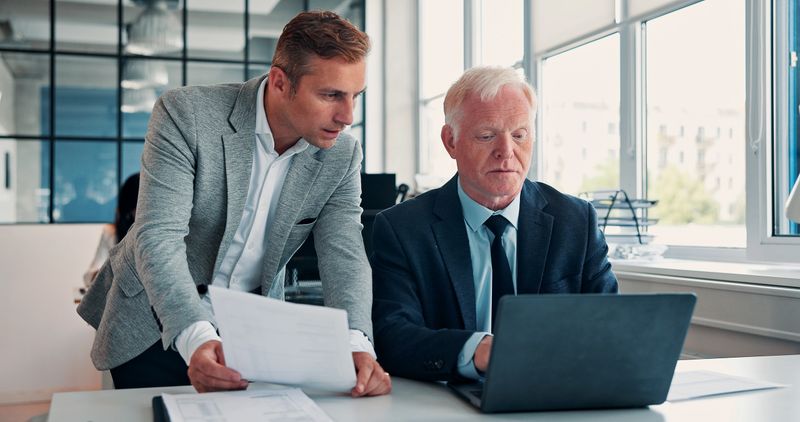 Documents, laptop and teamwork with business men at desk in office for accounting or finance.