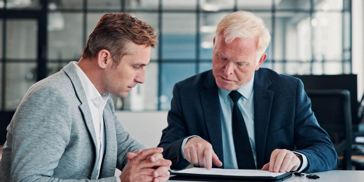 Dos hombres en una reunión de negocios revisando documentos.