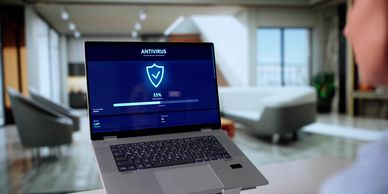 Person checking antivirus scan progress on laptop in a modern home.