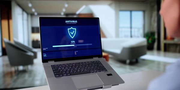 Laptop running antivirus software with a 53% scan progress in a modern room.