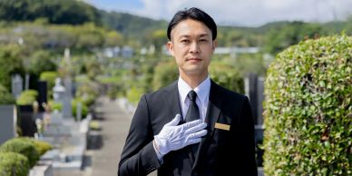 Man in suit with white glove in a cemetery.