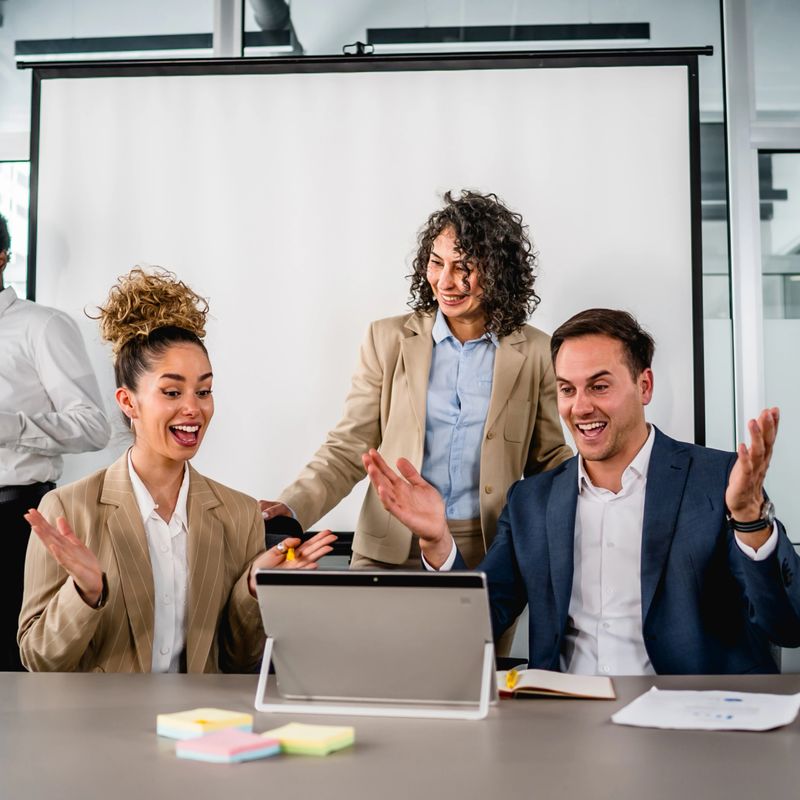 Excited business people celebrating success and good news during an online video call meeting in modern office