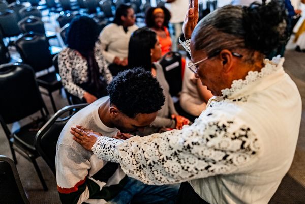 Four people in matching white polo shirts posing outdoors in front of a building.