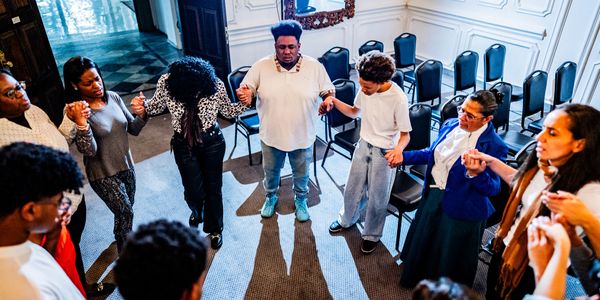 A diverse group holding hands in a circle for support or prayer.