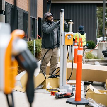 Technician installing an electric vehicle charging station outdoors.