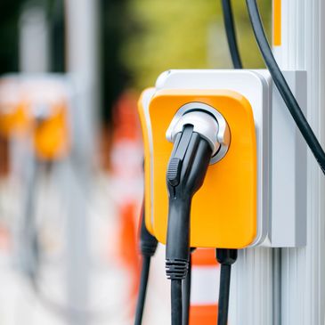 Close-up of an electric vehicle charging plug connected to a charging station.