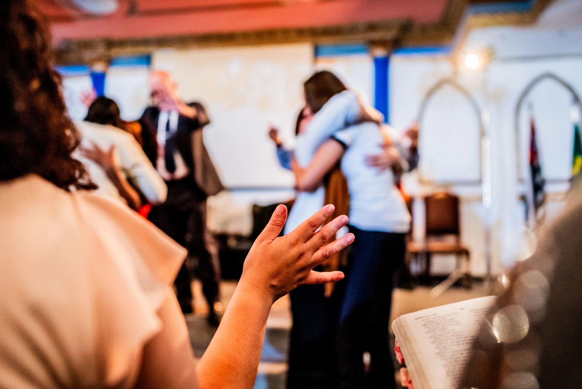 Hands clasped in prayer over a wooden table with 'PRAYER MINISTRY' text.