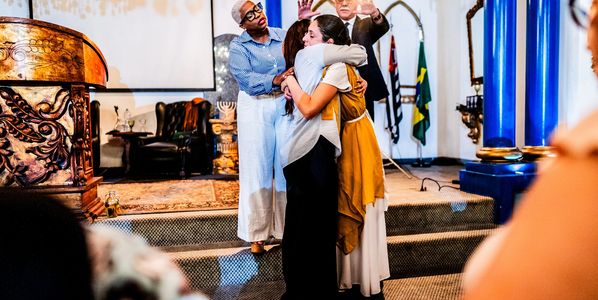 People with eyes closed, raising hands in a moment of prayer or worship.