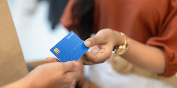 Person handing over a blue credit card.