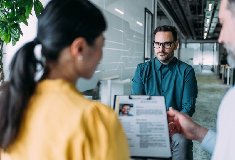Shot of a recruiters interview male candidate. Applicant presenting his resume to director while sitting with him at table during job interview. Employers accepting resume from an applicant.