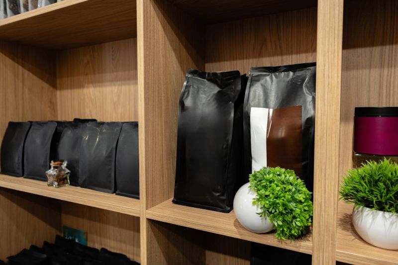 Different types of coffee are neatly arranged on wooden shelves alongside decorative plants.