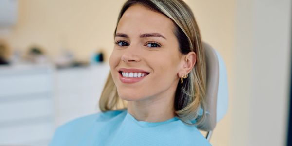 Smiling woman in a dental chair with a blue bib.