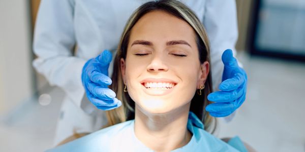 A smiling woman at the dentist, eyes closed.