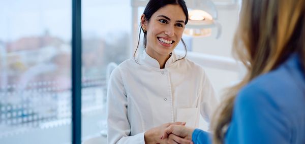 Smiling female healthcare professional shakes hands with patient.