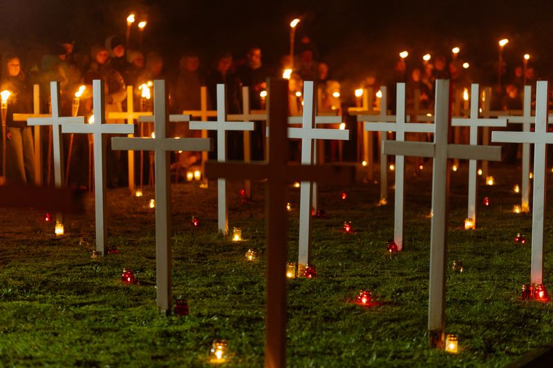 Memorial Cemetery with Crosses and Candlelight Vigil at Night