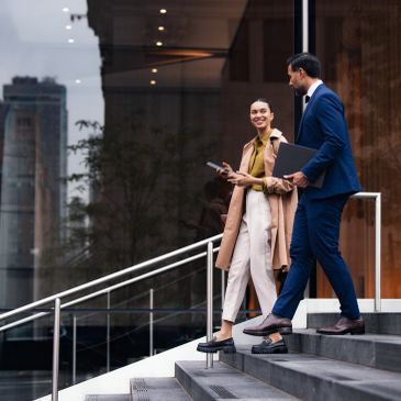 Two business professionals walking down outdoor stairs.