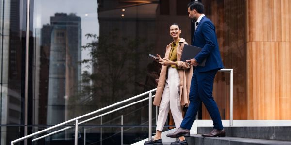 Two professionals walking down steps outside an office building.